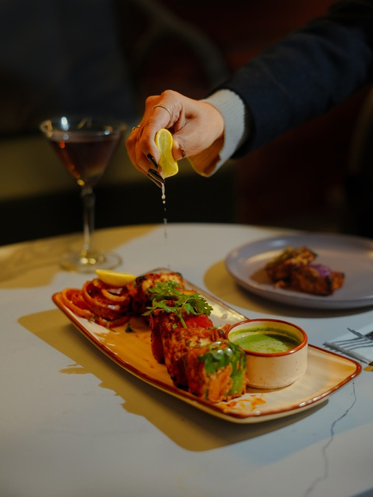 Lemon squeeze on tandoori dish — restaurant action photography